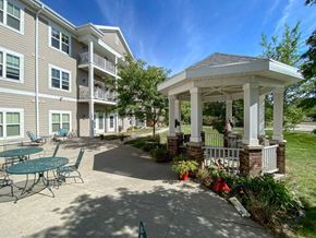 Johnston apartment for rent - A gazebo is surrounded by a building and a patio with chairs.at Cornerstone Commons, Johnston, IA 50131  