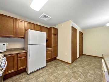 Johnston apartment for rent - A kitchen with a white refrigerator and brown cabinets.