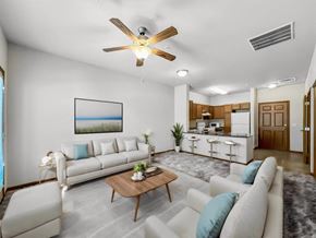 Johnston apartment for rent - A living room with a white couch, a coffee table, and a ceiling fan.at Cornerstone Commons, Johnston, IA 50131  