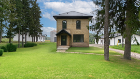 St. Agatha apartment for rent - A small house with a black roof is surrounded by a green lawn.
