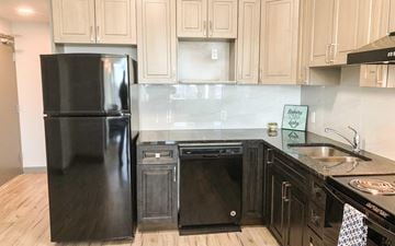 Waterloo apartment for rent - A black fridge and oven in a kitchen with wooden cabinets.
