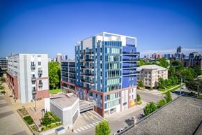 Waterloo apartment for rent - A modern multi-story building with blue and white panels is surrounded by other buildings and greenery.