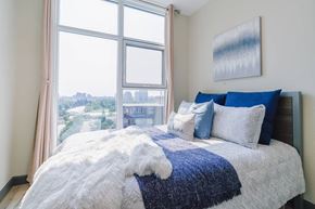 Waterloo apartment for rent - a bedroom with a large window and a bed with blue and white pillows