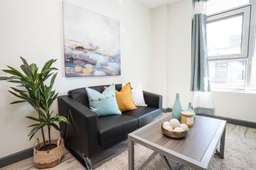 Waterloo apartment for rent - A living room with a black couch, a wooden coffee table, and a large painting on the wall.