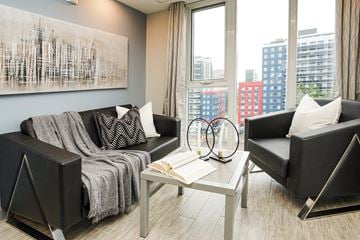 Waterloo apartment for rent - A living room with a grey couch, a black chair, and a coffee table with a book on it.
