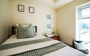Waterloo apartment for rent - A bed with a green and white striped blanket and a green pillow is in the foreground of the image.