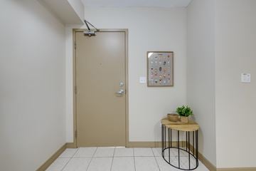 Waterloo apartment for rent - A room with a brown door, a small table with a plant and a picture on the wall.