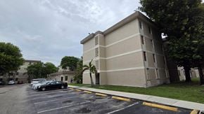 Hialeah apartment for rent - A parking lot in front of a beige building.
