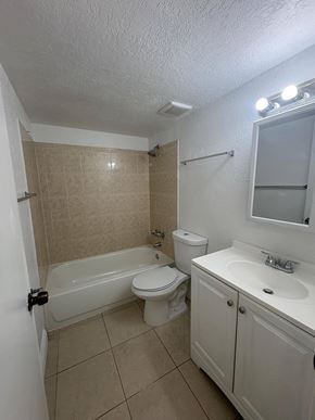 Hialeah apartment for rent - A white bathroom with a toilet, sink, and bathtub.