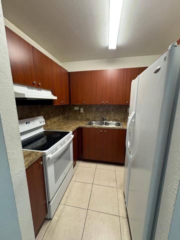 Hialeah apartment for rent - A kitchen with brown cabinets and a white refrigerator.