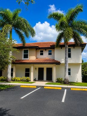 Bonita Springs apartment for rent - A two-story house with a red tile roof and a palm tree in front.