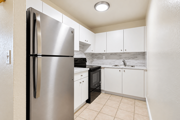 Miami apartment for rent - A kitchen with a stainless steel refrigerator and white cabinets.