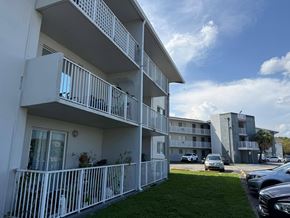 Cutler Bay apartment for rent - A white apartment building with balconies and cars parked in the background.