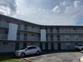 Cutler Bay apartment for rent - A silver car is parked in a parking lot in front of a white building.