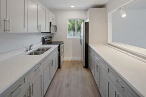 Boca Raton apartment for rent - a kitchen with white cabinets and a black refrigerator