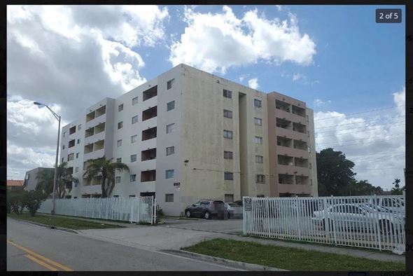 Hialeah apartment for rent - a large white building with cars parked in front of it
