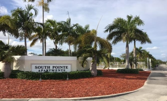Miami apartment for rent - a sign for south point apartments in front of palm trees