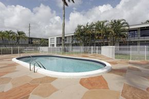 Oakland Park apartment for rent - a swimming pool in front of a building with palm trees