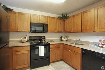 Oakland Park apartment for rent - A kitchen with wooden cabinets and black appliances.