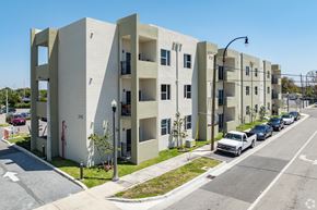 Hialeah apartment for rent - A street view of apartment buildings with cars parked on the side of the road.
