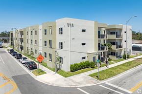 Hialeah apartment for rent - A street view of a residential area with apartment buildings and cars parked on the side of the road.