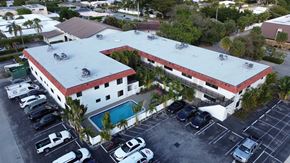 Lighthouse Point apartment for rent - A large white building with a red roof and a pool in the courtyard.