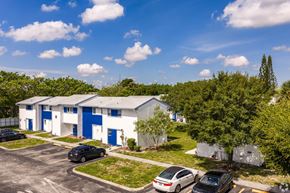 Riviera Beach apartment for rent - A parking lot with cars and a building with blue doors.