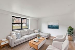 Albany apartment for rent - A living room with a large window, a white couch, a coffee table, and a painting on the wall.