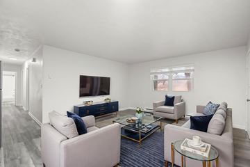 Staunton apartment for rent - A living room with a grey couch, a blue sofa, a glass coffee table and a television on the wall.