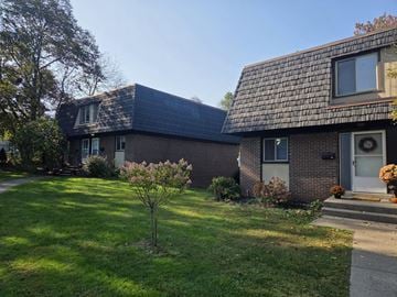 Syracuse apartment for rent - A house with a grey roof and a small tree in front of it.