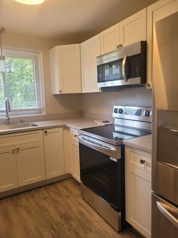 Syracuse apartment for rent - A kitchen with white cabinets and a black microwave above the stove.