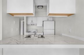 Fort Myers apartment for rent - A kitchen with white cabinets and a marble countertop.
