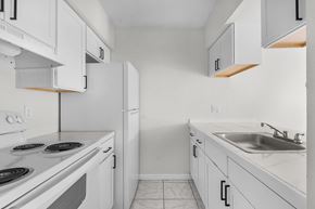 Fort Myers apartment for rent - A white kitchen with a stove, sink, and cabinets.