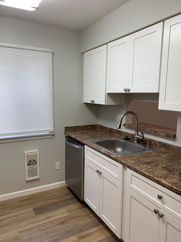 Manlius apartment for rent - A kitchen with white cabinets and a granite countertop.