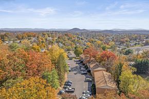 Staunton apartment for rent - A view of a residential area with a parking lot and houses surrounded by trees with autumn foliage.