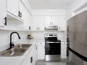 Cape Canaveral apartment for rent - a kitchen with white cabinets and a sink and a stove