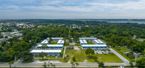 Merritt Island apartment for rent - an aerial view of three buildings with trees and a body of water in the background