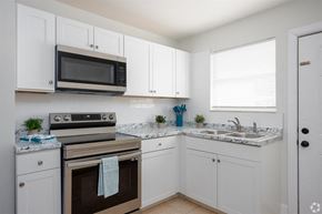 Titusville apartment for rent - a kitchen with white cabinets and a stove and a microwave