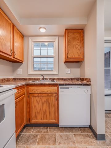 Baldwinsville apartment for rent - A kitchen with wooden cabinets and a white dishwasher.