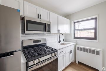 Albany apartment for rent - A white kitchen with a stove, oven, microwave, and refrigerator.