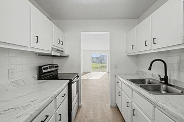 Merritt Island apartment for rent - A kitchen with white cabinets and marble countertops.
