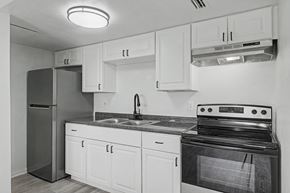 Merritt Island apartment for rent - A black and white photo of a kitchen with white cabinets and a black stove.