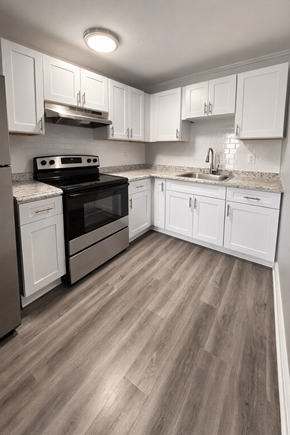 Milton apartment for rent - A kitchen with white cabinets and a black stove top oven.