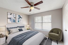 Pensacola apartment for rent - A bedroom with a bed, a chair, and two framed pictures on the wall.