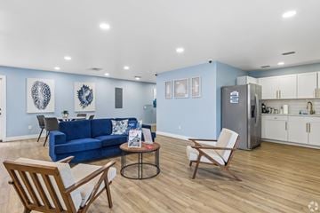 Fort Myers apartment for rent - A blue couch sits in a living room with a kitchen in the background.