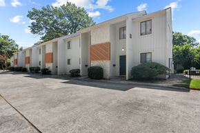 Macon apartment for rent - A building with a white and brown exterior is surrounded by a parking lot.