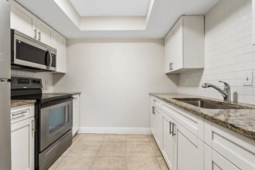 Fort Myers apartment for rent - A kitchen with white cabinets and a black microwave.