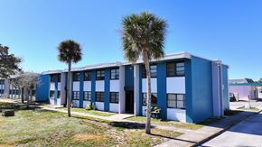 Cape Canaveral apartment for rent - A blue and white building with a palm tree in front.