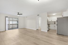 Fort Myers apartment for rent - A spacious room with a ceiling fan and lighting, leading to a kitchen area.