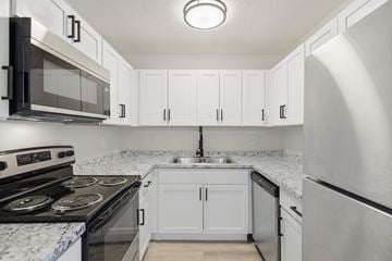 Fort Myers apartment for rent - A kitchen with white cabinets and a marble countertop.